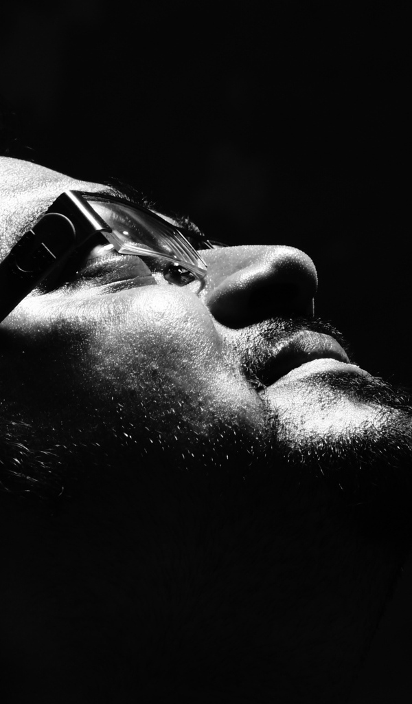 Мужчина в очках смотрит вверх на черном фоне