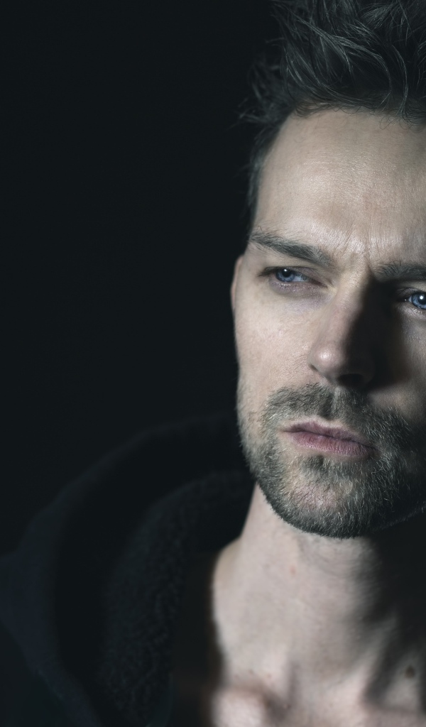 Серьезный голубоглазый мужчина на черном фоне