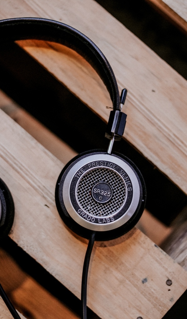 Старые наушники лежат на деревянной лавке