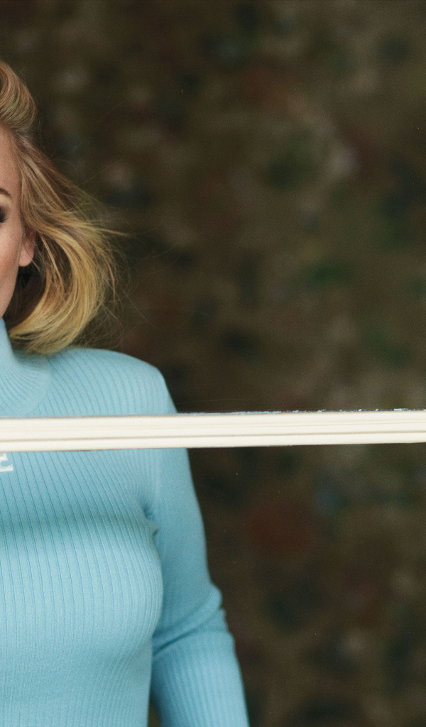 Певица Адель стоит у окна