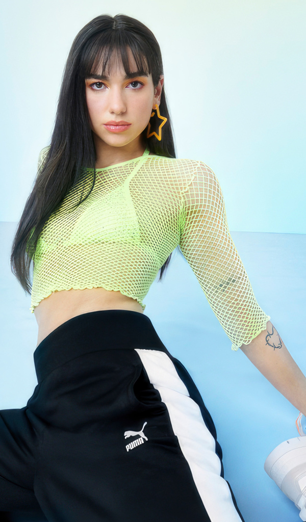 Певица Дуа Липа в штанах Puma на голубом фоне