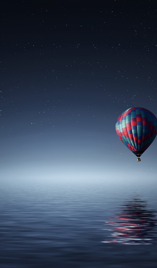 Большой воздушный шар летит над водой ночью