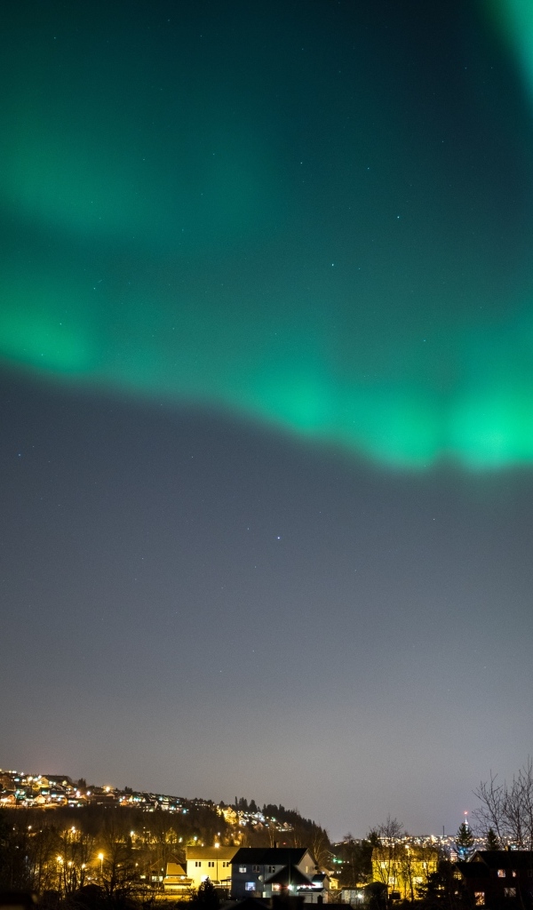 Зеленое полярное сияние в небе над ночным городом