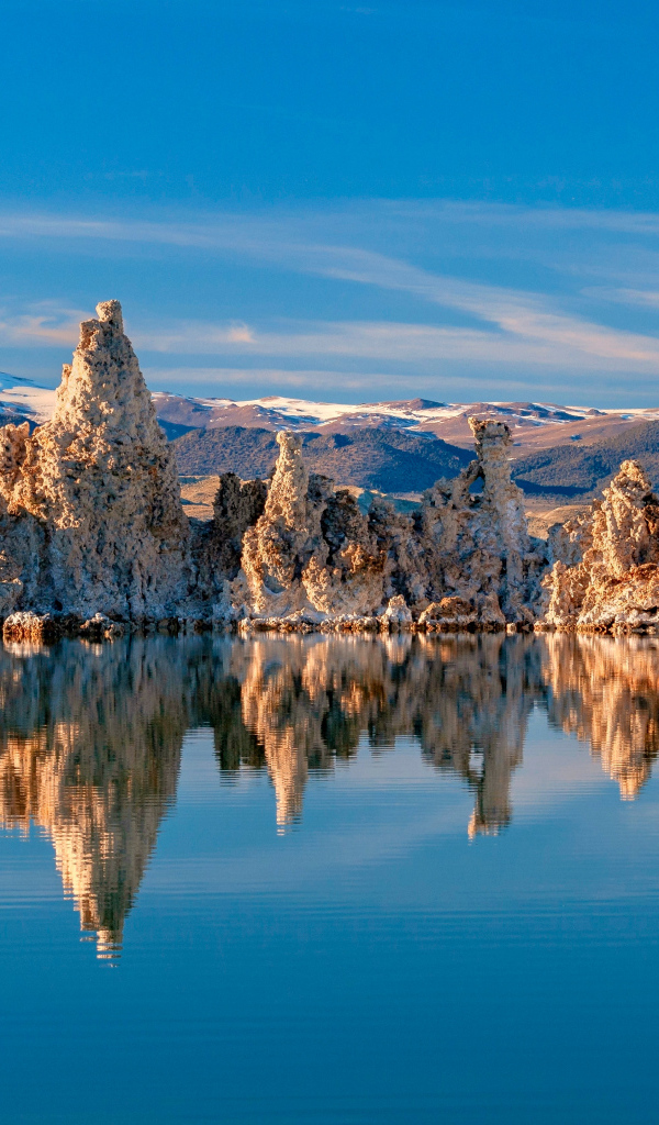 Острые скалы отражаются в тихой воде озера