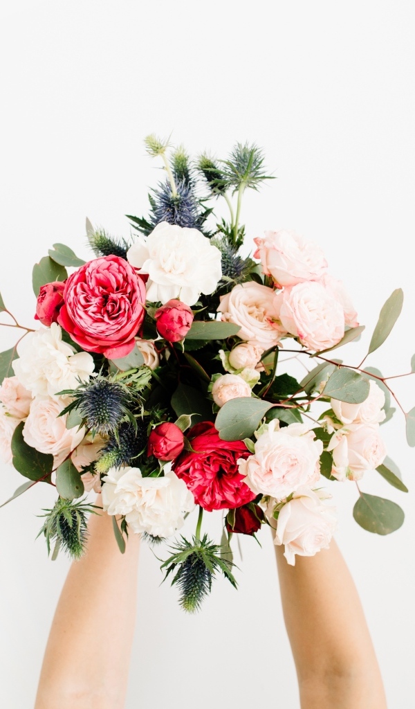 Букет цветов в руках у девушки на сером фоне