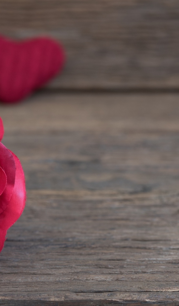 Искусственная роза на деревянном фоне с сердечками