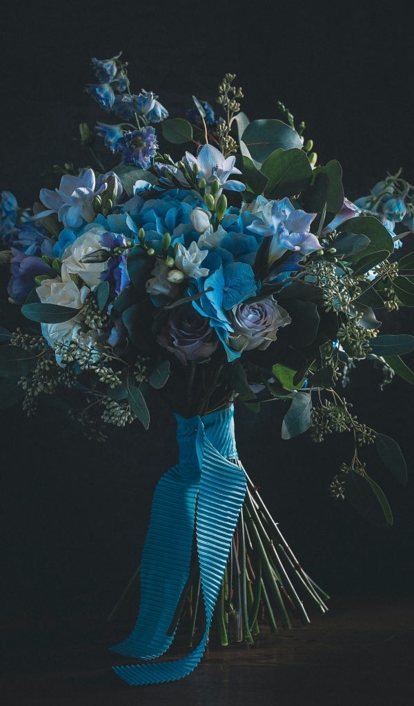 Красивый букет цветов с голубой лентой у стены