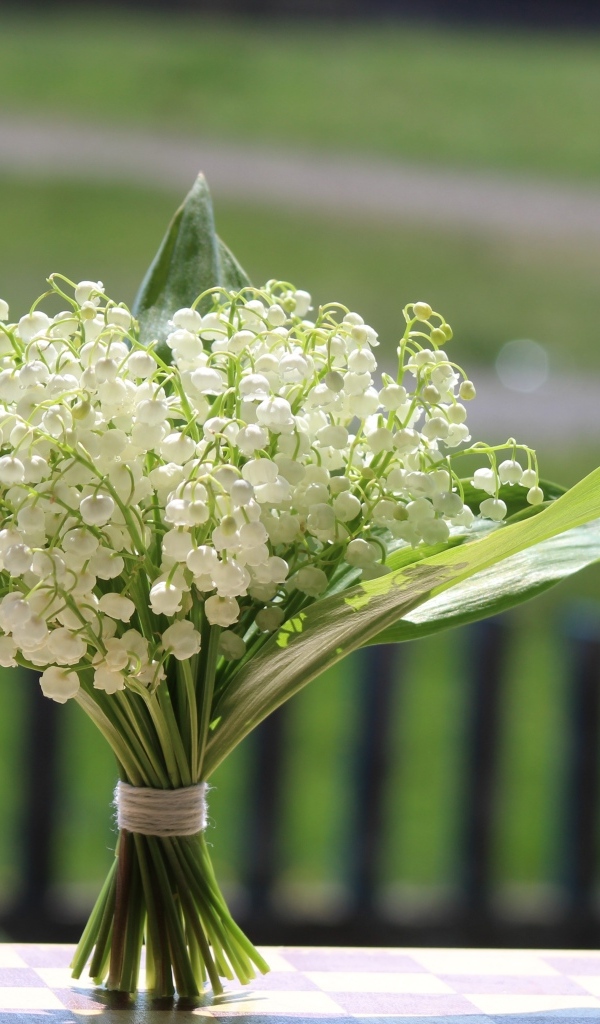 Красивый букет белых ландышей на столе в вазе