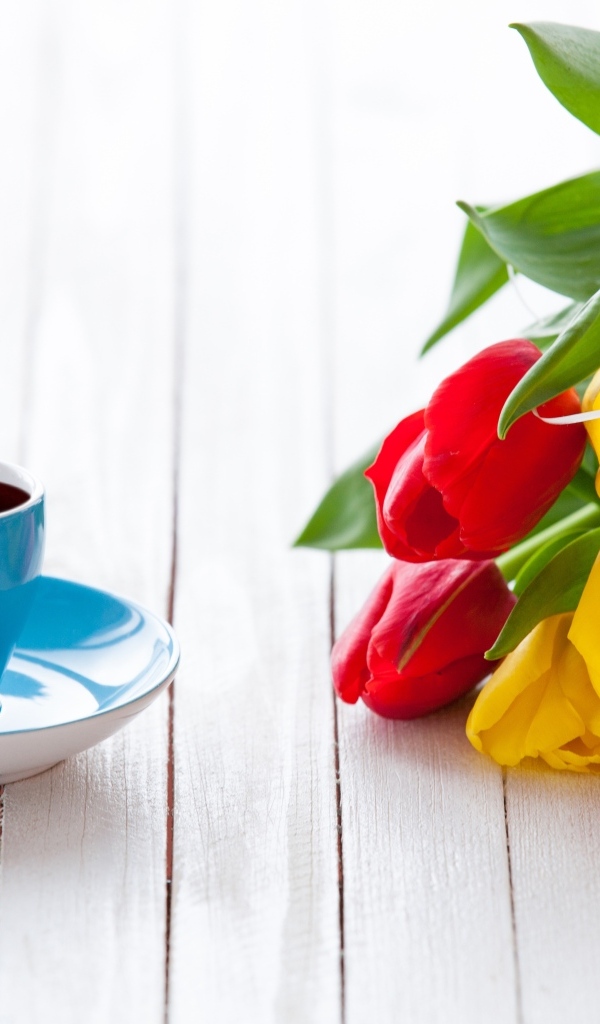 Голубая чашка на столе с букетом тюльпанов