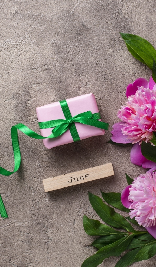 Букет розовых пионов с подарком на сером столе