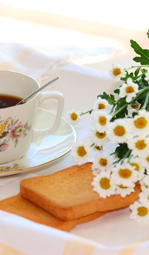 Букет белых ромашек с чашкой чая  и хлебом