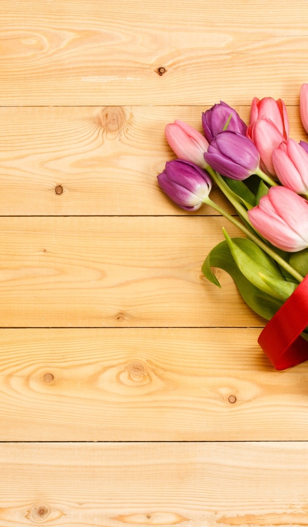 Большой букет тюльпанов с красной лентой на деревянном фоне