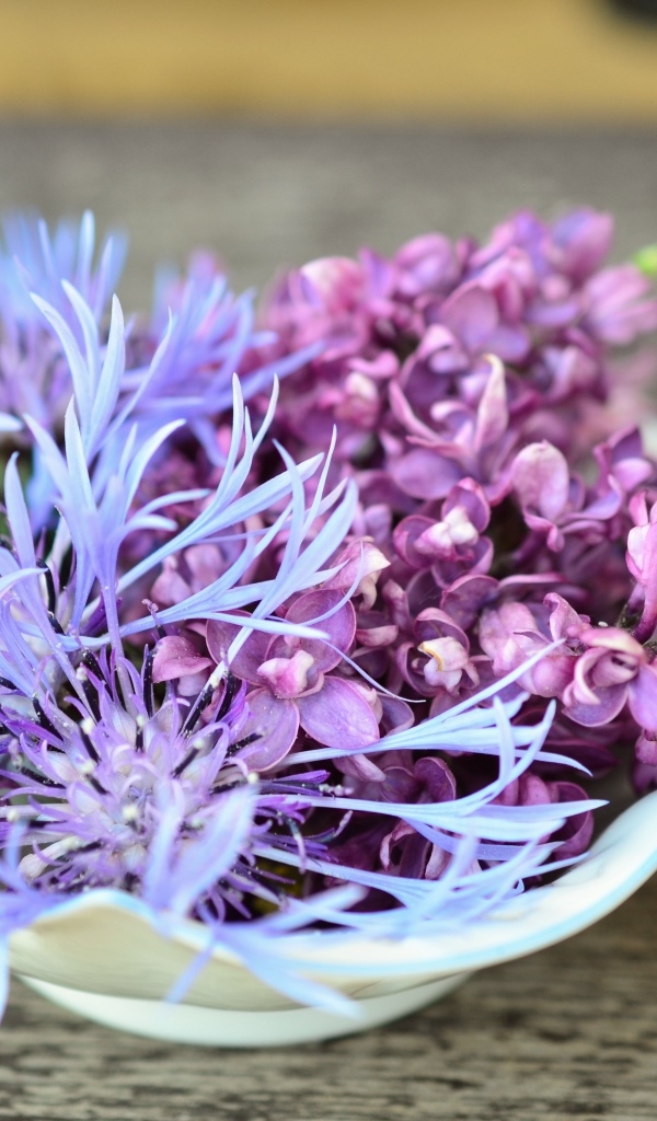 Цветы сирени и василька в вазе на столе