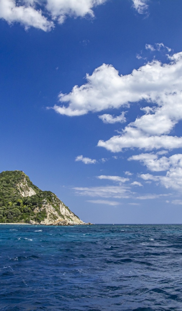 Покрытые зеленью горы в море под голубым небом