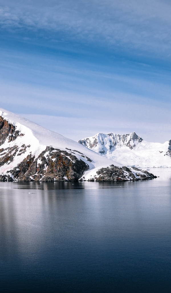 Заснеженная гора на берегу моря под голубым  небом