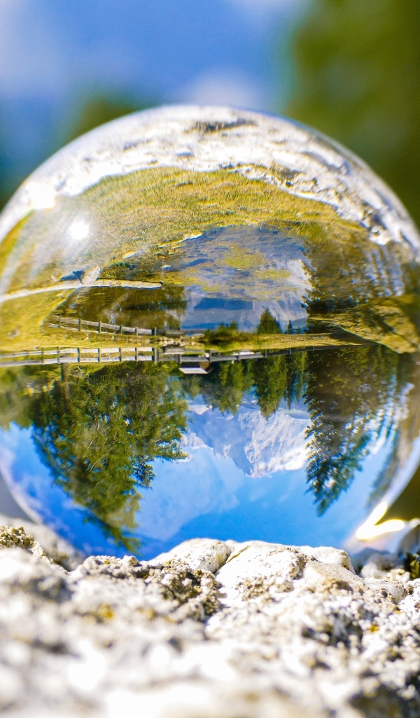 Стеклянный шар стоит на камне у воды