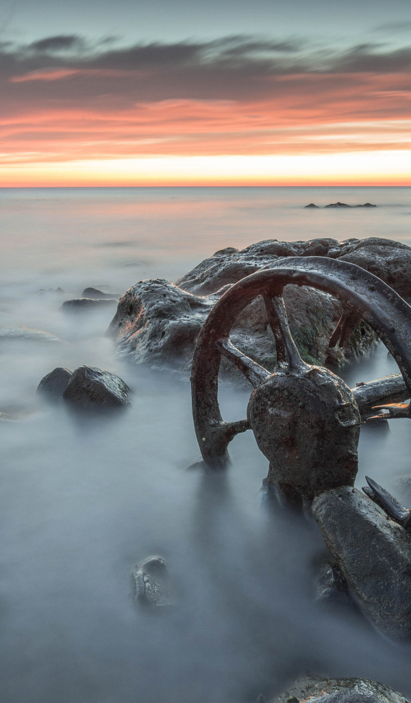 Старые колеса лежат в воде с камнями