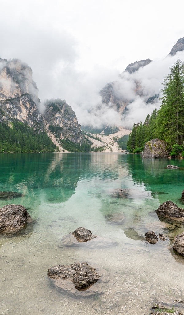 Камни лежат в воде озера в холодных горах