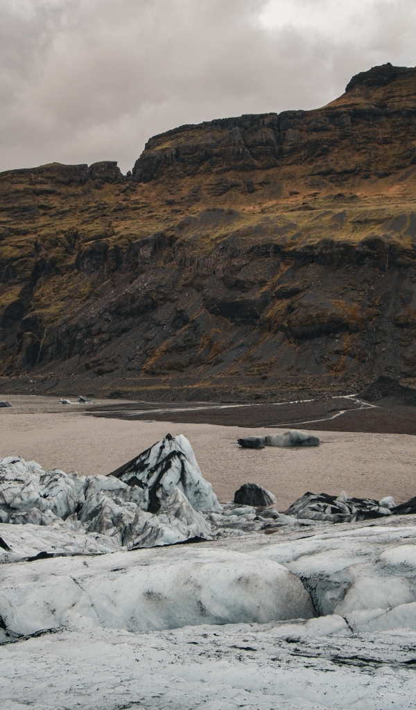 Холодный грязный снег на берегу моря у гор 