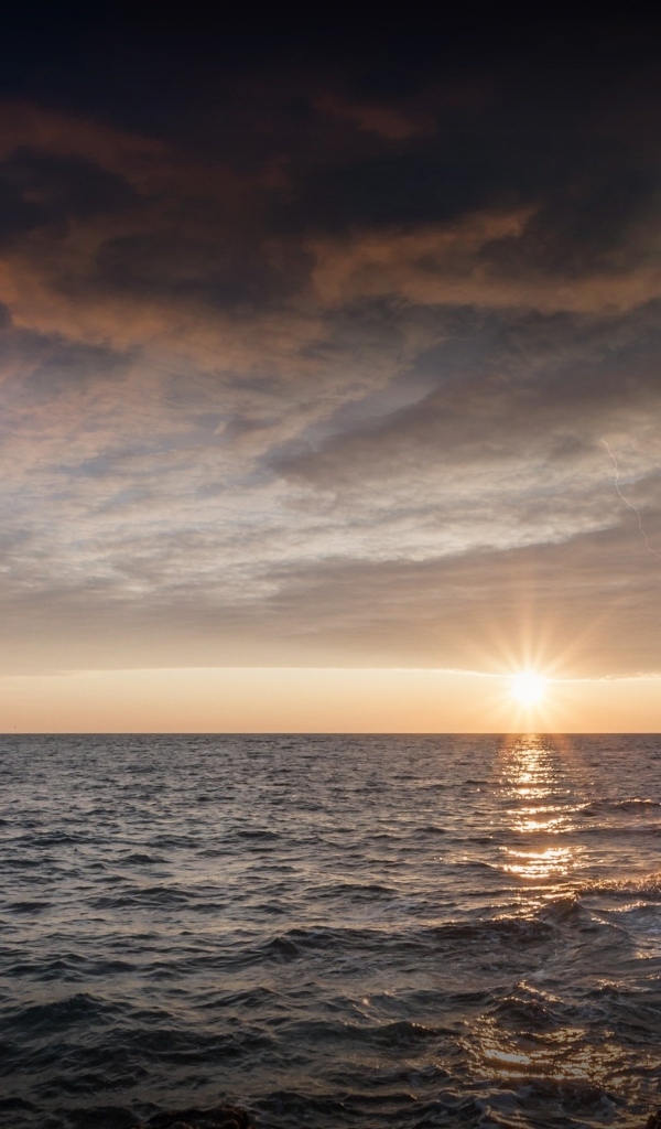 Высокий маяк на берегу моря на закате