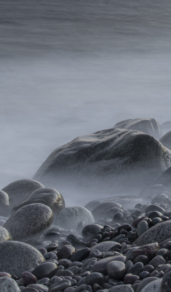 Большие черные камни на берегу моря в тумане