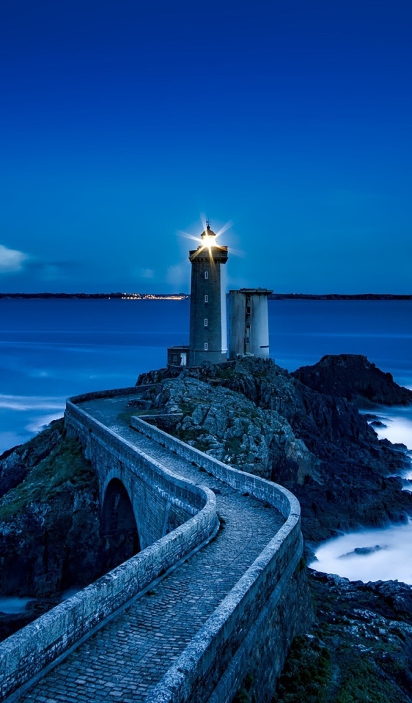 Зажженный маяк на берегу моря ночью