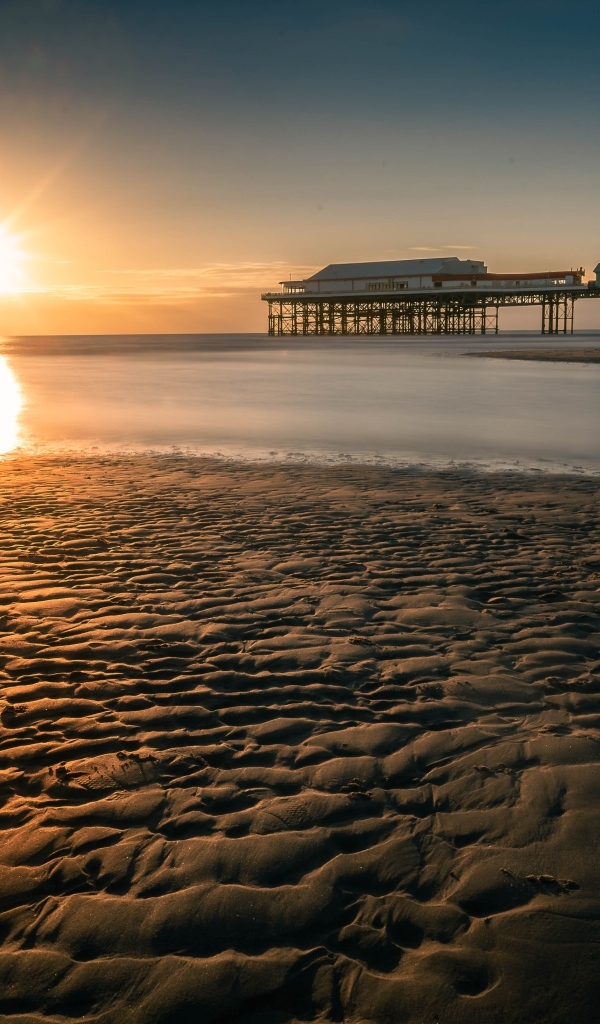 Мокрый песок на берегу моря на закате