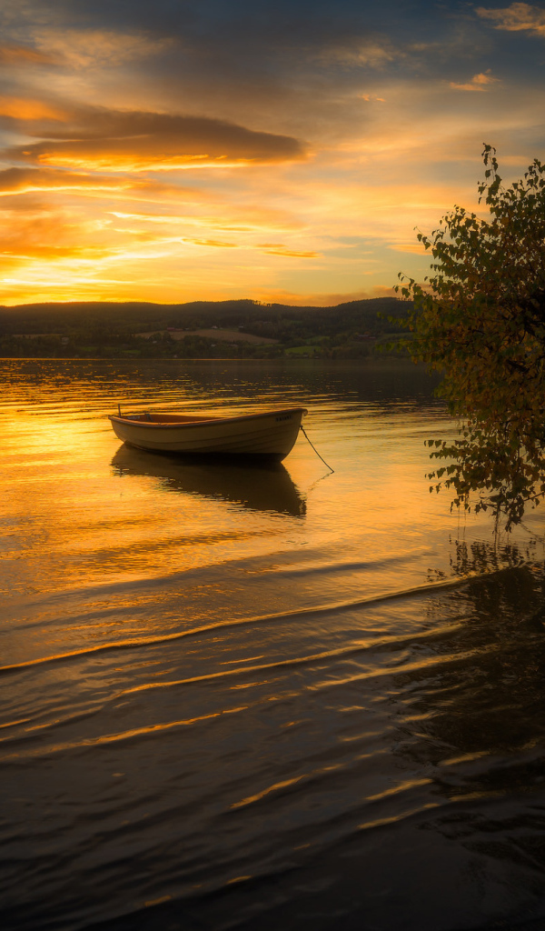 Лодка в воде спокойного озера на закате солнца