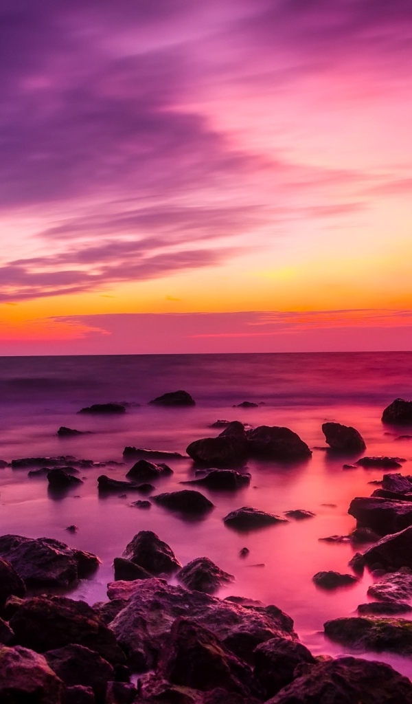 Розовый закат на каменном берегу моря
