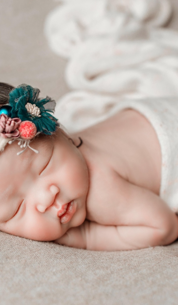 Новорожденная девочка азиатка спит на сером покрывале