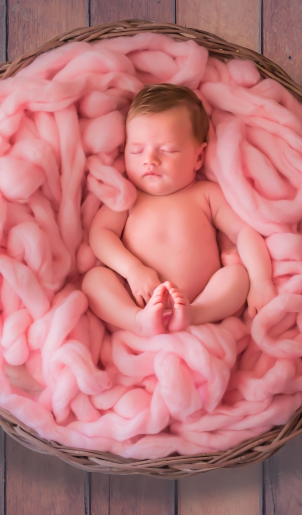 Ребенок спит в корзине с розовым покрывалом