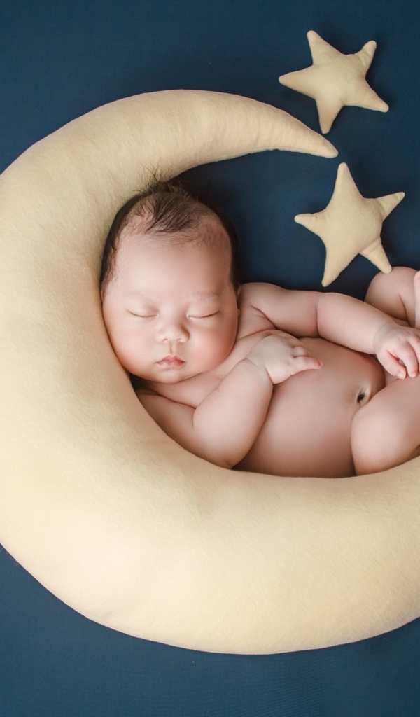 Ребенок спит на игрушечном месяце