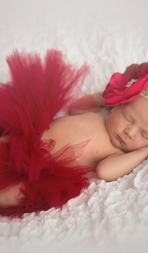 Красивая пышная красная юбка и бант на спящей малышке