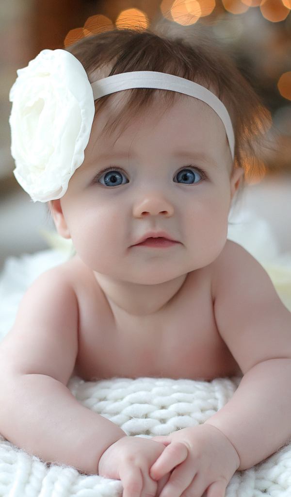 Красивая маленькая девочка с белым цветком на голове