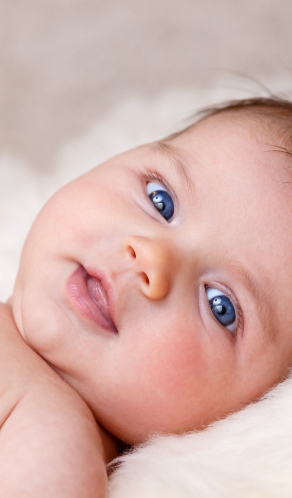 Голубоглазая новорожденная малышка с цветком на голове