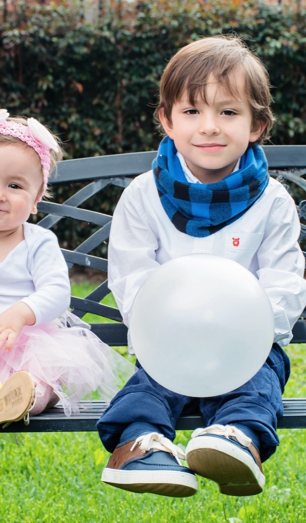 Мальчик и девочка сидят на лавке в парке