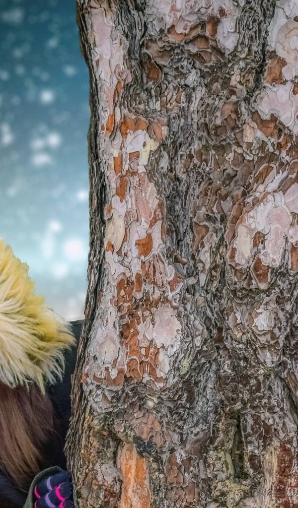 Мальчик и девочка стоят у дерева зимой