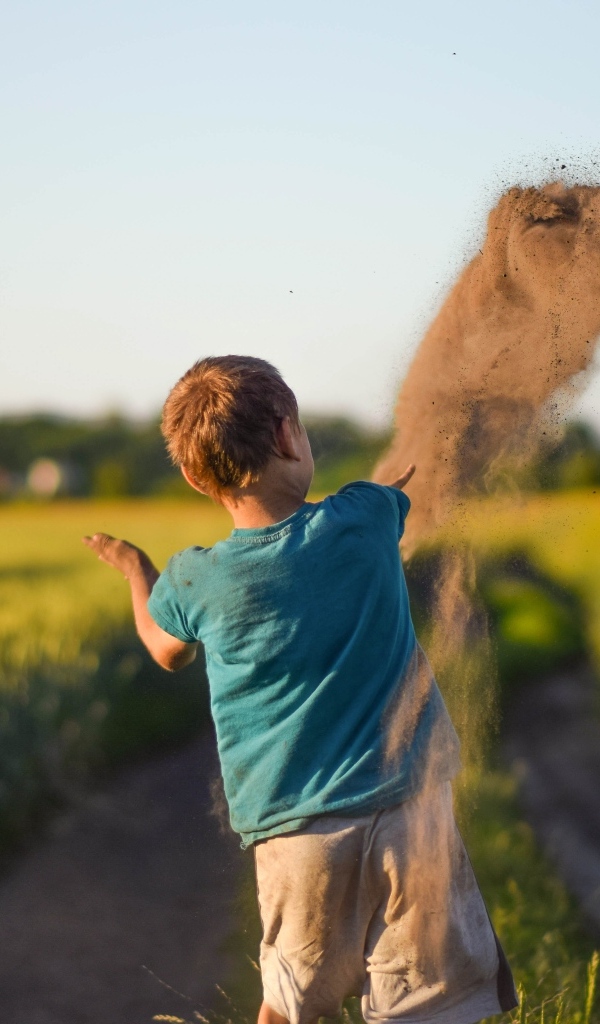 Мальчик бросает песок на дороге