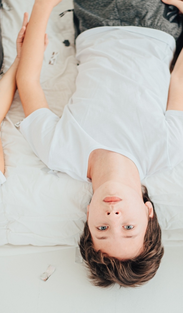 Дети в белых футболках лежат на кровати