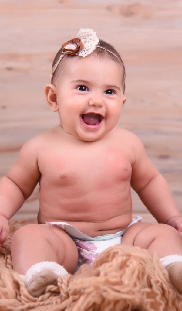 Милый улыбающийся ребенок на фоне деревянной стены