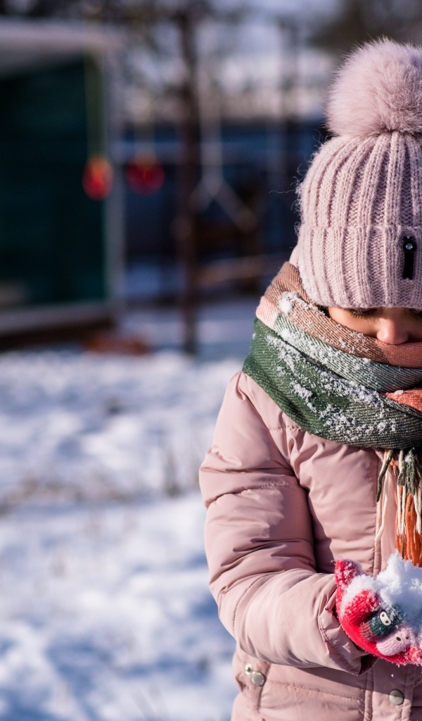 Девочка держит снег в руках зимой