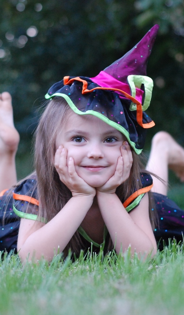 Девочка в костюме лежит на зеленой траве