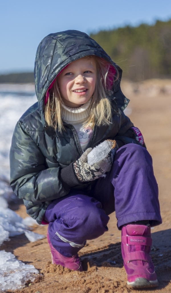 Девочка сидит у замерзшего озера 