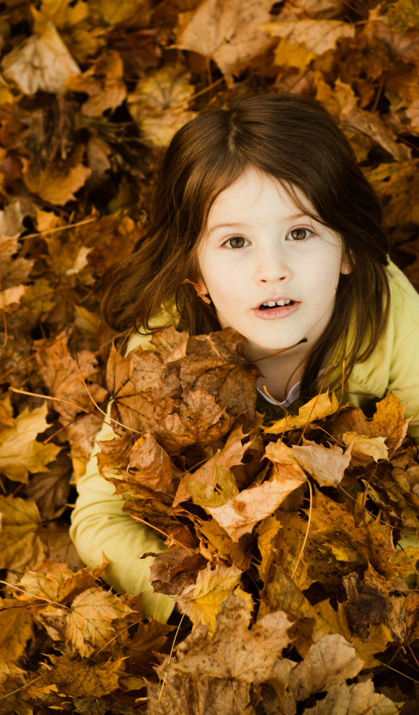 Девочка сидит в опавшей листве