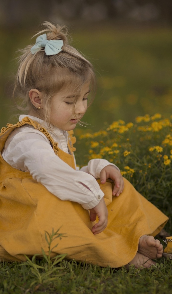 Девочка сидит на траве с игрушечной машинкой