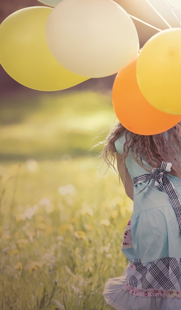 Девочка с шариками бегает по траве