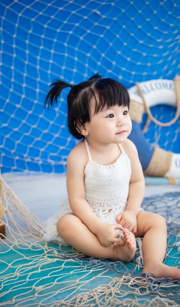 Маленькая девочка азиатка со  спасательным кругом и сетью 