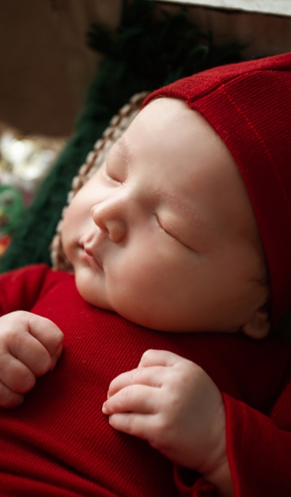 Маленький ребенок спит в красном костюме