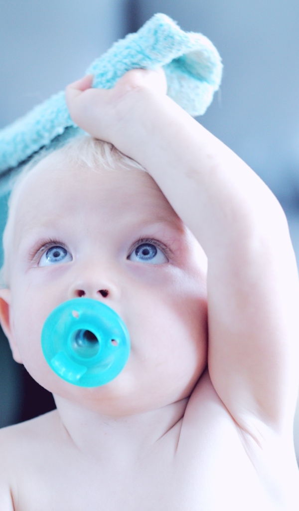 Маленький ребенок с голубой соской во рту