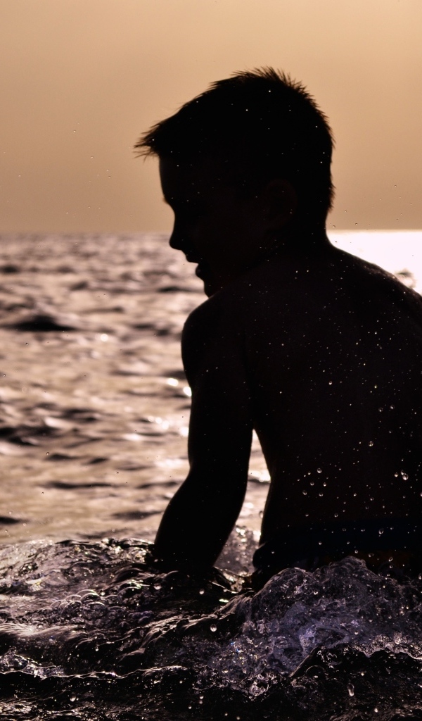 Маленький мальчик купается в воде летом